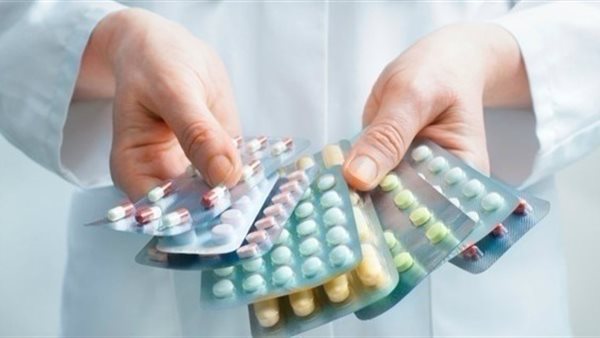 A person holding multiple pills and tablets in their hand.