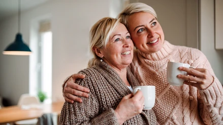 Two women holding coffee cups, smiling.