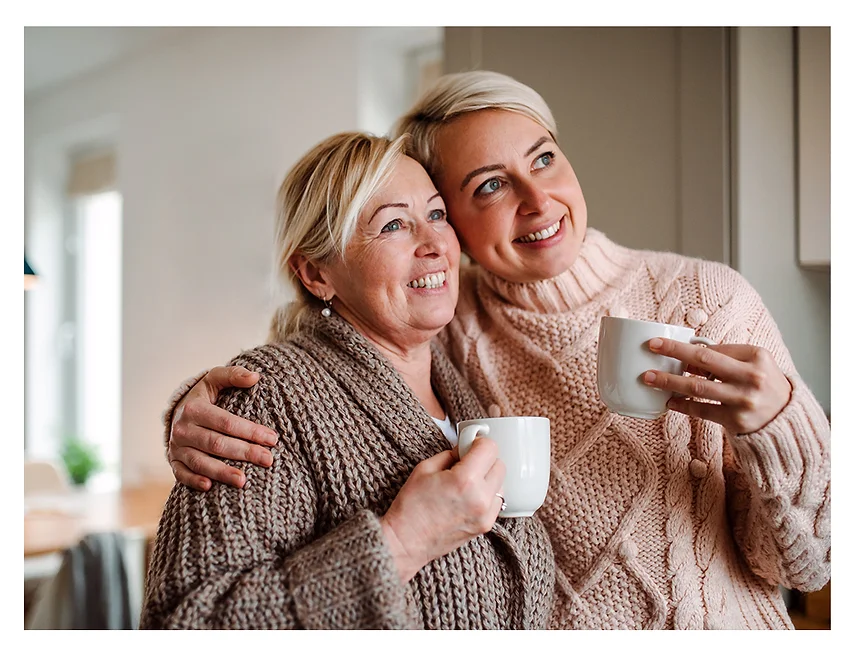 Two women holding coffee cups, smiling.